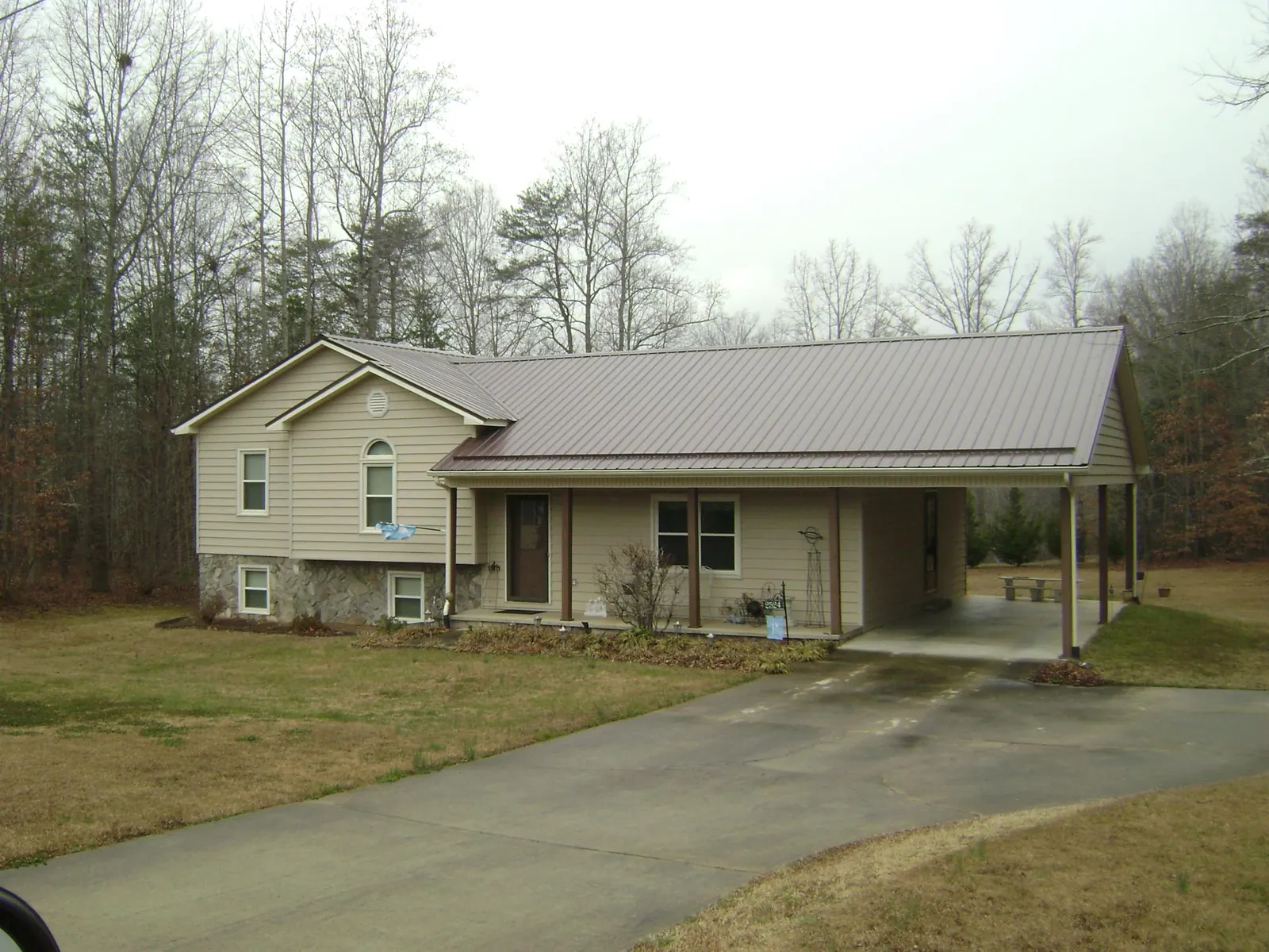 Brown metal roof on a tan split level home with an attached carport in Lebanon